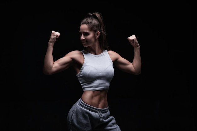 Athletic fitness woman posing in the studio on a dark\
background photo of an attractive woman in fashionable sportswear\
sports and healthy lifestyle