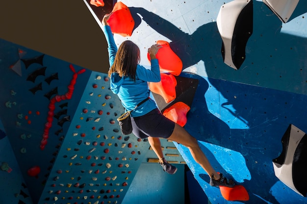Foto ragazza atletica che si arrampica su una parete da arrampicata al coperto