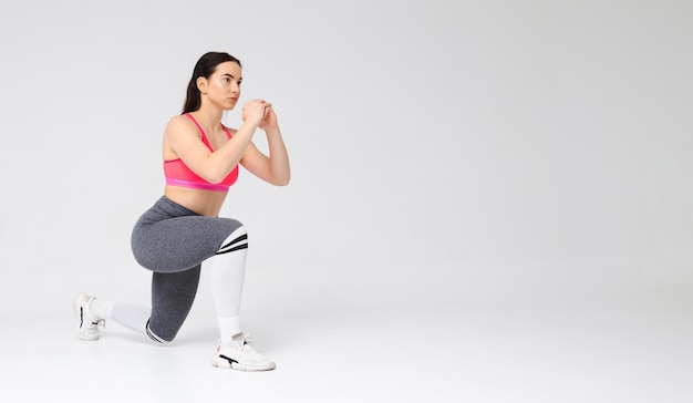 Athletic girl doing lunges in the studio on a white background