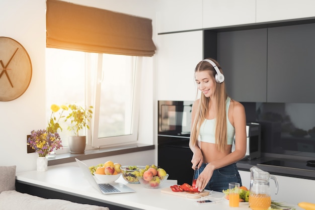 Спортивная девушка стоит на кухне и готовит салат