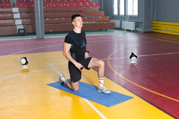 Athletic guy in sportswear and fitness tracker doing exercises in gym