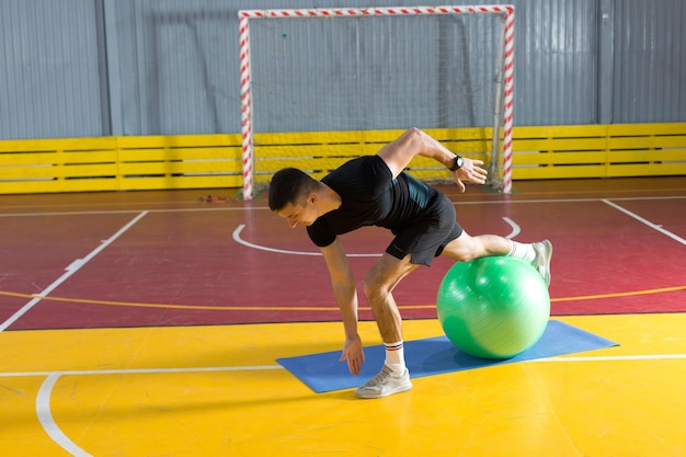 Athletic guy in sportswear and fitness tracker doing exercises in gym