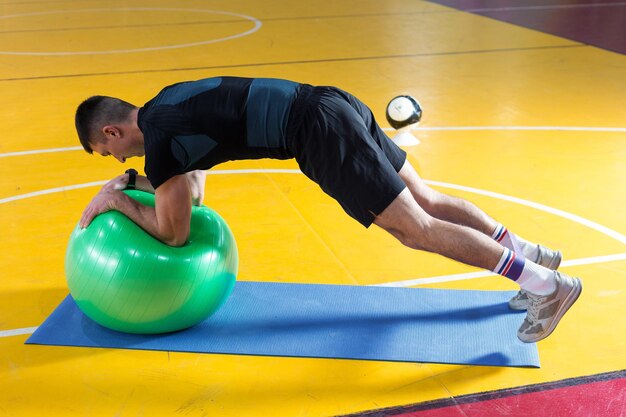 Спортивный парень в спортивной одежде и фитнес-трекере делает упражнения в тренажерном зале