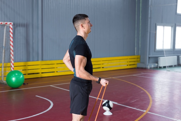 Athletic guy in sportswear and fitness tracker doing exercises in gym.