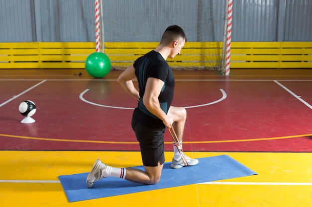 Спортивный парень в спортивной одежде и фитнес-трекере делает упражнения в тренажерном зале.