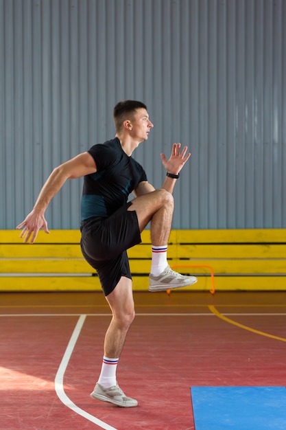 Спортивный парень в спортивной одежде и фитнес-трекере делает упражнения в тренажерном зале.