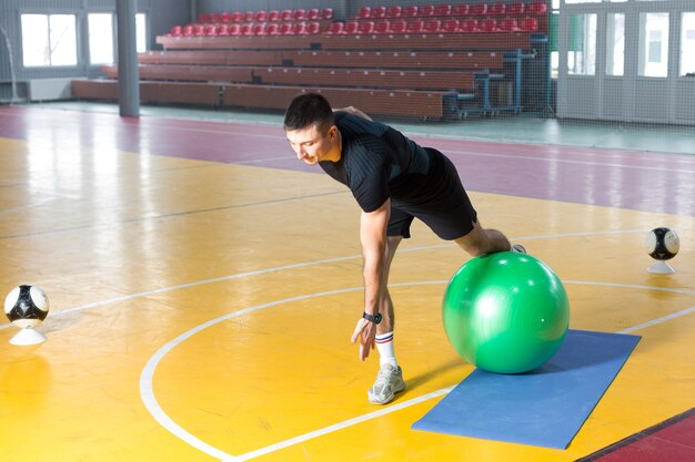 Спортивный парень в спортивной одежде и фитнес-трекере делает упражнения в тренажерном зале.