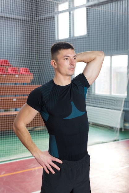 Спортивный парень в спортивной одежде и фитнес-трекере делает упражнения в тренажерном зале.