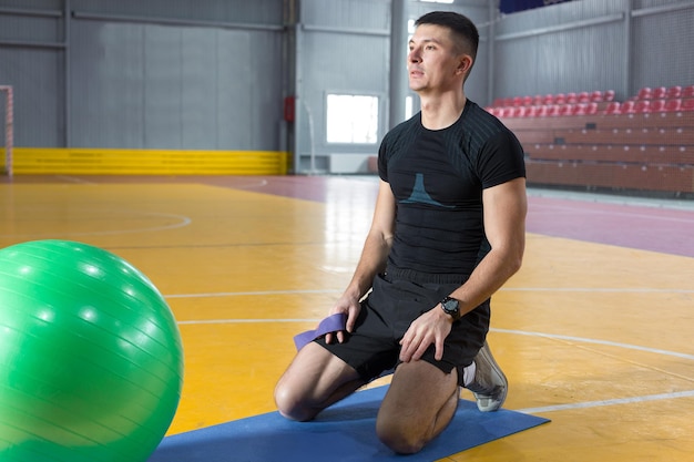 Athletic guy in sportswear and fitness tracker doing exercises in gym.