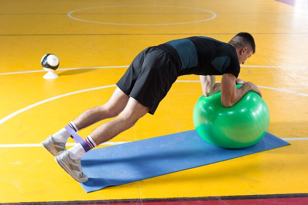 Athletic guy in sportswear and fitness tracker doing exercises in gym.