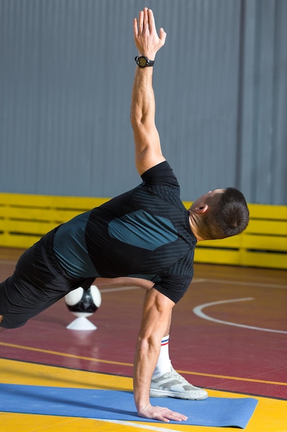 Спортивный парень в спортивной одежде и фитнес-трекере делает упражнения в тренажерном зале.