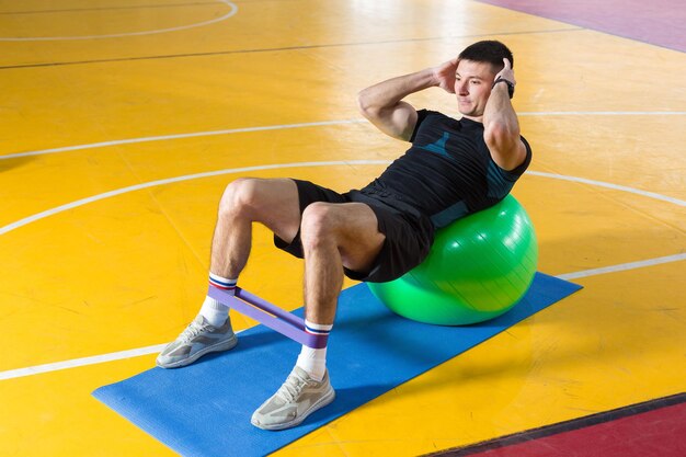 Athletic guy in sportswear and fitness tracker doing exercises in gym