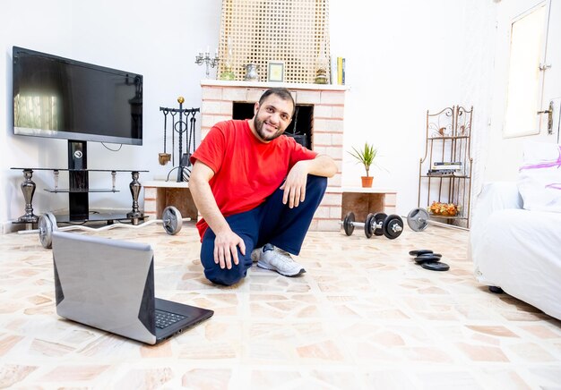 Athletic guy watching video tutorial to work out