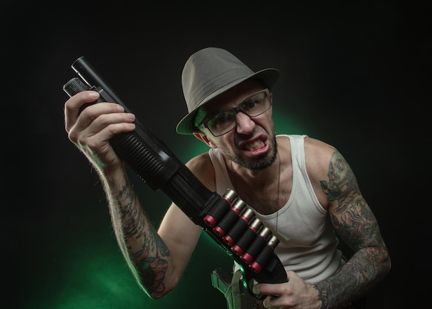 The athletic guy with a tattoo poses with a shotgun