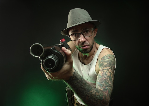 The athletic guy with a tattoo poses with a shotgun