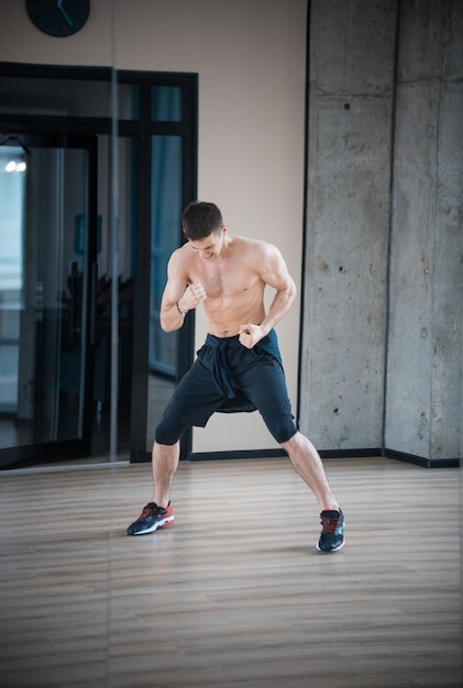 An athletic half naked man boxer training in the studio