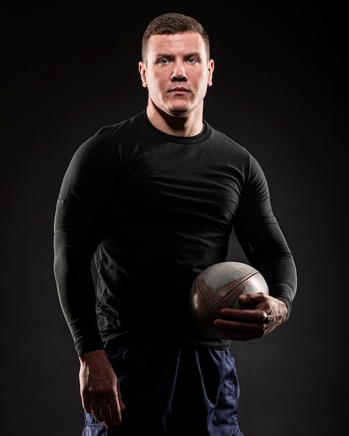 Photo athletic male rugby player posing while holding ball