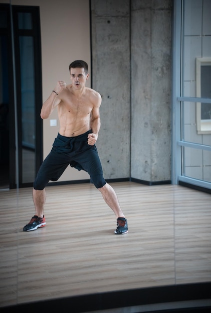 An athletic man boxer training in the bright studio