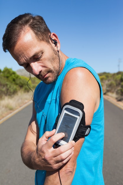 Athletic man changing the music on a run