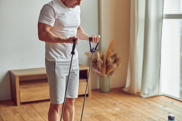 Athletic man doing domestic training with eqipment