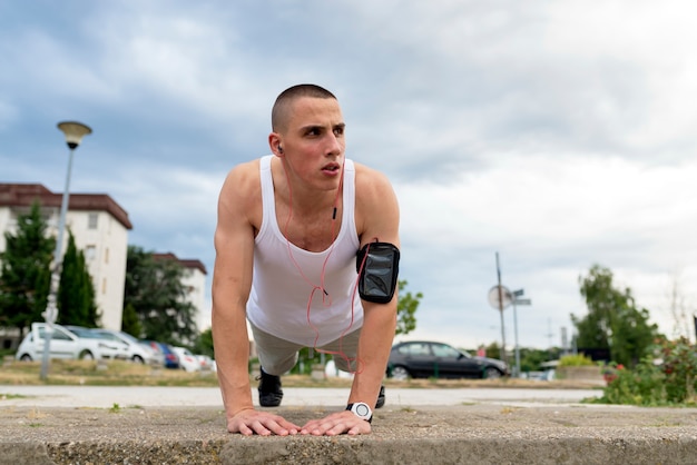 Athletic man doing push-up on a road at sunset.