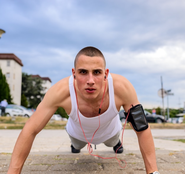 Athletic man doing push-up on a road at sunset.