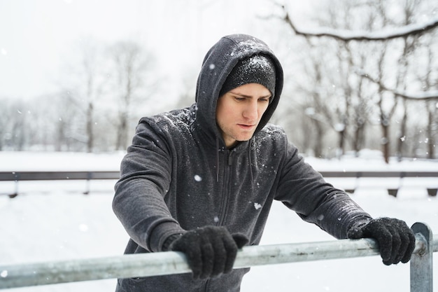 Athletic man doing push ups during his calisthenics winter workout in snowy park