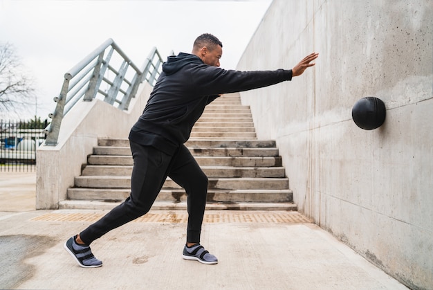 Athletic man doing wall ball exercise.