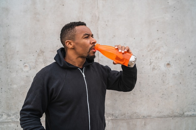 Athletic man drinking something after training.