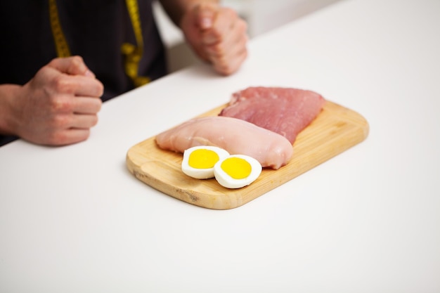 Athletic man holding a board with meat for proper nutrition of the athlete.