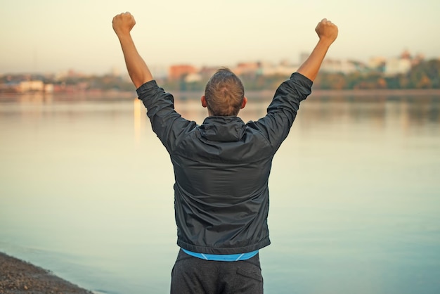 athletic man is happy and rejoicing at the beach raised his hands up winner