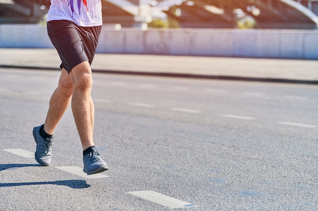 Athletic man jogging in sportswear on city road