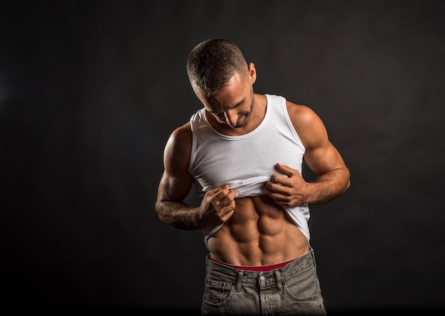 Athletic man lifting his shirt to show his abs.