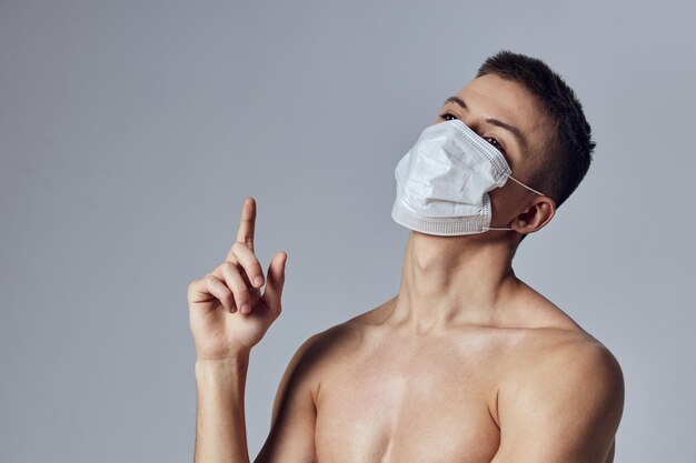 Athletic man naked shoulders showing thumbs up medical mask posing