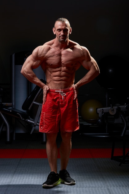 Athletic man posing. Photo of man with perfect physique on black