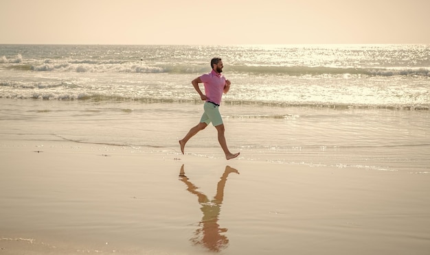 Athletic man runner running barefoot on summer beach sport