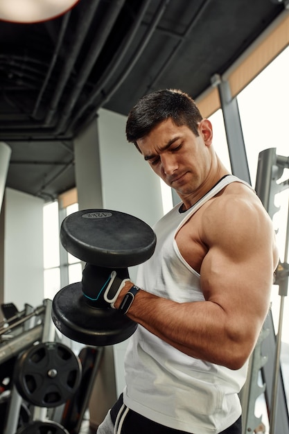 Athletic man shakes his biceps with dumbbell in his hands Healthy lifestyle concept