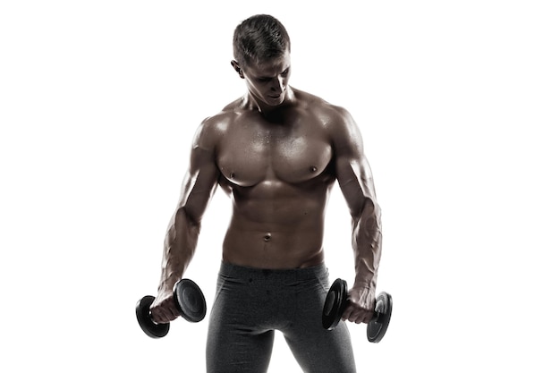 Спортивный (ый) мужчина показывает мускулистое тело и делает упражнения с гантелями