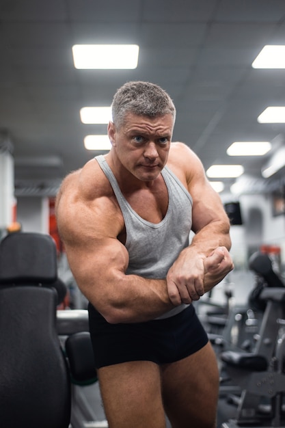 Спортивный человек демонстрирует свои мышцы в тренажерном зале