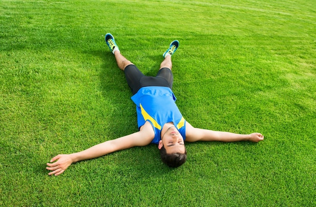 Athletic man sitting on the grass and relaxing