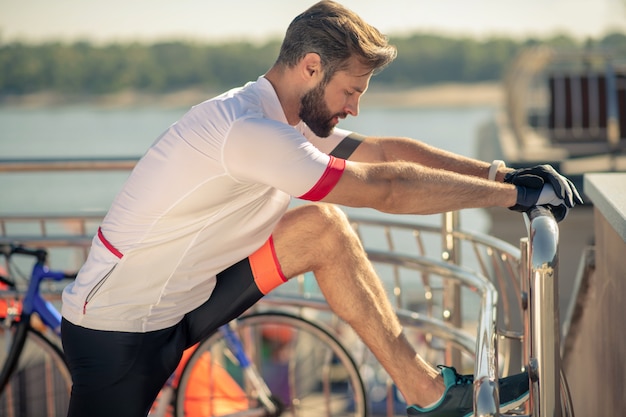 Athletic man in sportswear stretching out on street