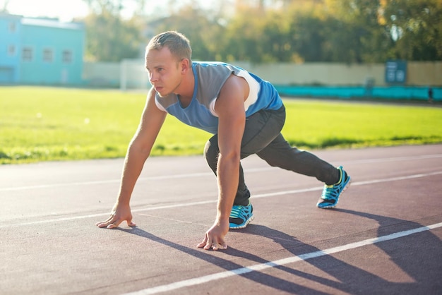 Photo athletic man standing in posture ready to run on a treadmill