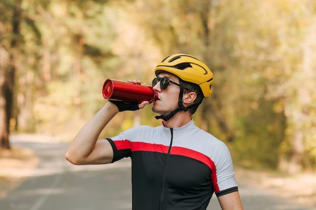 Athletic man stands on the road with a bicycle