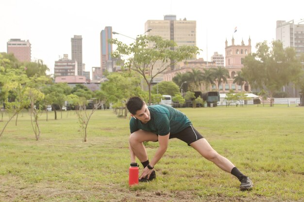 街を背景に公園でストレッチをするアスレチック男。