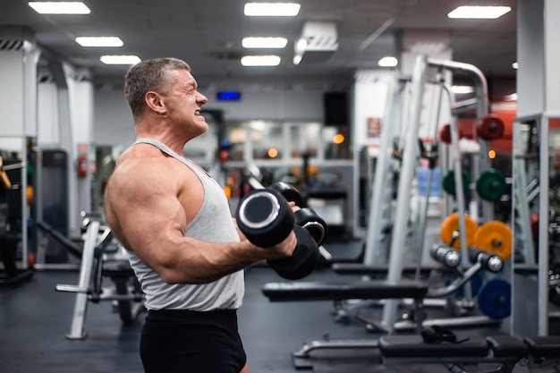 Athletic man trains in the gym. 