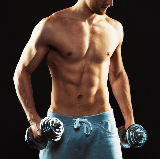 Athletic man with dumbbells on the black