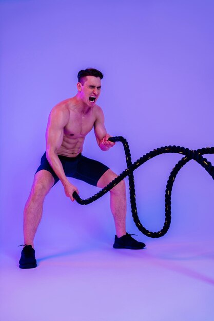 Athletic man with fit muscular body training in studio