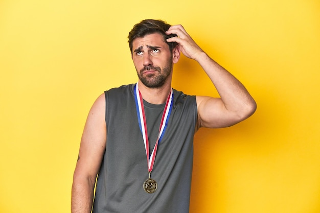 Athletic man with gold medal yellow studio backdrop being shocked