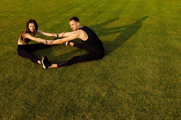 Athletic man and woman doing different exercise on green lawn High quality photo