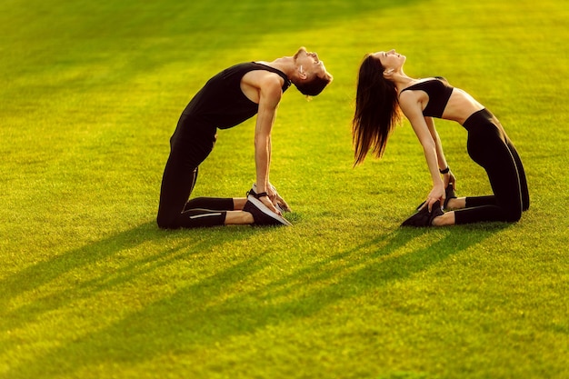 Спортивные мужчина и женщина делают разные упражнения на зеленой лужайке Фото высокого качества